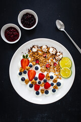 Yogurt with strawberries, blueberries, raspberries and muesli in bowl on wooden table
