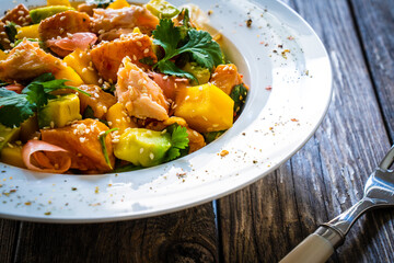 Salmon ceviche with lemon, mango and avocado on wooden table