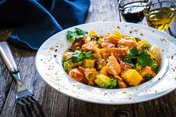 Salmon ceviche with lemon, mango and avocado on wooden table