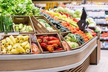 Supermarket showcase with wooden boxes of vegetables. Organic fresh broccoli, paprika, lettuce, onion. Concept of bio food and shopping in grocery store