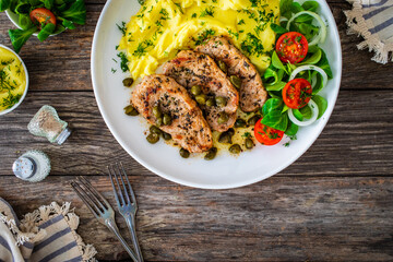 Fried pork loin with mashed potatoes and vegetables on wooden table
