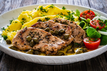 Fried pork loin with mashed potatoes and vegetables on wooden table
