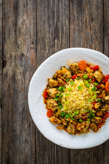 Fried chicken nuggets, bulgur groats, carrots and red pepper on wooden background
