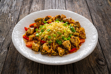 Fototapeta premium Fried chicken nuggets, bulgur groats, carrots and red pepper on wooden background 