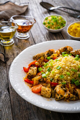 Fried chicken nuggets, bulgur groats, carrots and red pepper on wooden background
