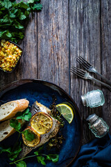 Roast sea bream with bread and lemon on wooden table
