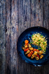 Fried chicken nuggets, bulgur groats, carrots and red pepper on wooden background
