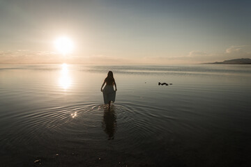 silhouette of a girl in blue dress standing in salt lake, utah, USA, at sunset