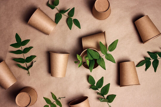 Set of eco-friendly coffee to go cups with green leaves on brown paper background.
