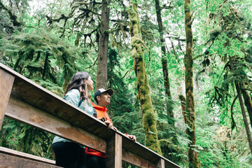A young couple enjoys a hike in a forest in the Pacific Northwest.
