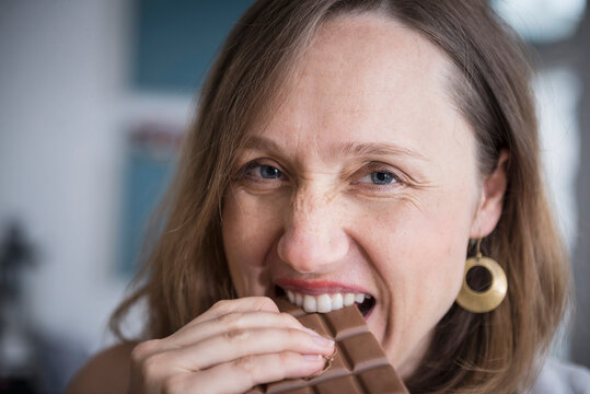 Portrait of a pregnant woman eating chocolate in the kitchen, Munich, Bavaria, Germany