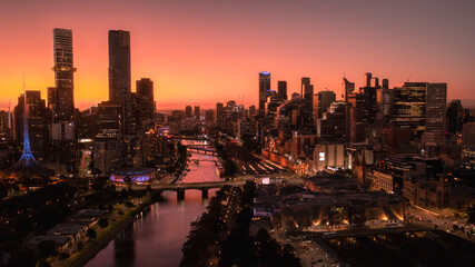 Melbourne City Skyline Panoramic View at sunset. The sky has blue, purple and orange layered hues with orange reflections of the facades of buildings.
