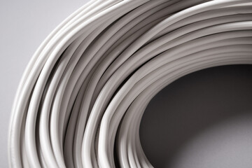 Roll of white electric cable wire on grey background