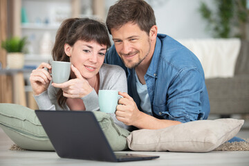young couple using a laptop on the floor