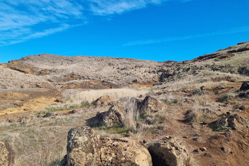 Volcanic land on the island of Madeira against the backdrop of a blue sky.