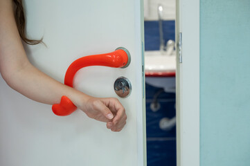 Door handle for people with disabilities. The woman opens the door with her wrist.
