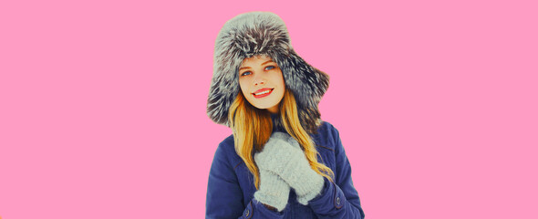 Portrait of beautiful young blonde woman in winter hat on pink background