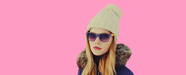 Winter portrait of beautiful young blonde woman wearing hat on pink background