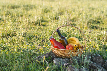 picnic basket with wine, juice and fruits on green grass