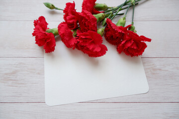 Red Carnation decoration with blank greeting card on wooden background. floral background for Mother's day, Women's day and Valentine's day. 