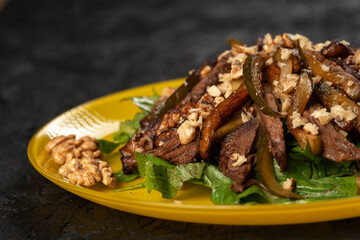 beef salad with vegetables and walnut on black background