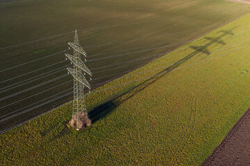 Power supply pole on farmland with powerlines and cables