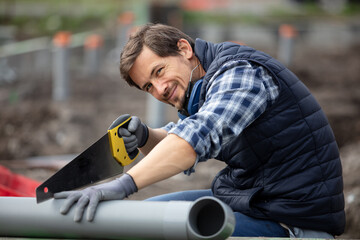 worker holding sewage pipes outdoors