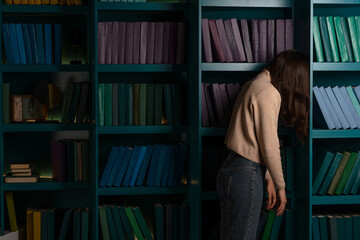 Sad student on the background of bookshelves. Exam stress. academic failures and loss of motivation.