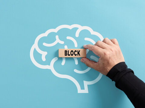 Mental block concept. To remove or generate mental blocks of the human mind. Hand puts a wooden block with the word block on a human brain symbol.