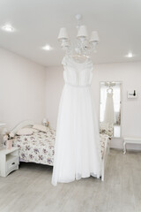 Fototapeta na wymiar bride's wedding dress hanging on a chandelier in a bright interior