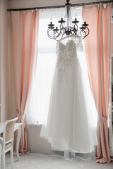 wedding dress hanging in bright interior