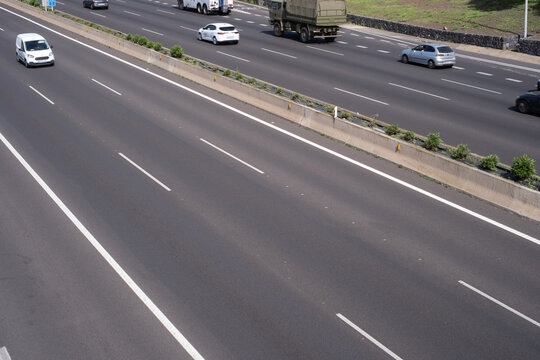 Road markings, solid lines and dashed lines, marking different lanes, on the dark asphalt floor of a highway. Tenerife, Canary Islands, Spain.