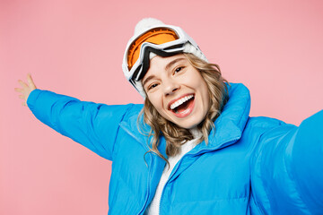 Close up snowboarder woman in blue suit goggles mask hat ski padded jacket do selfie shot pov mobile cell phone isolated on plain pastel pink background Winter extreme sport hobby trip relax concept