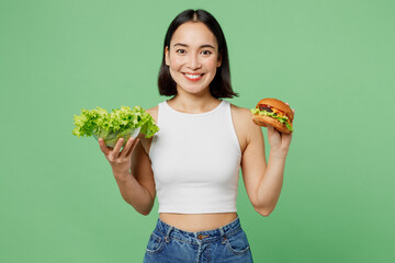 Young smiling happy woman wear white clothes hold eat burger fresh greens lettuce leaves isolated...