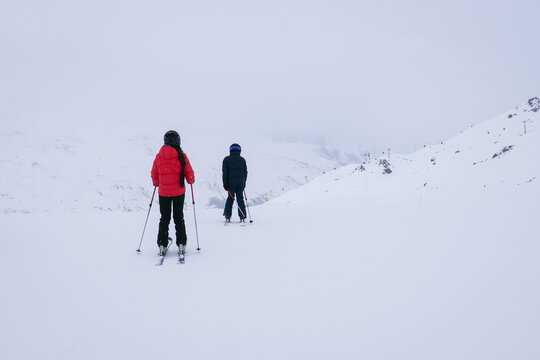 girl and boy skiiing in winter landscape in french alps on foggy day