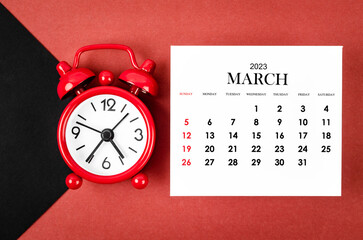 The March 2023 Monthly calendar year with alarm clock on red and black background.