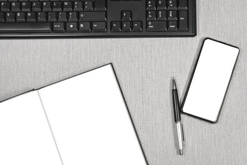 Livre ouvert et un smartphone sans inscription avec un clavier d'ordinateur.