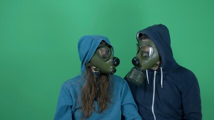 Man and woman with gas mask looking to each other, green screen, sad future,