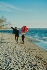 young couple with a red heart balloons on the beach, st. Valentines Day
