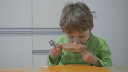 Funny dirty kid licking the plate after finished the cake