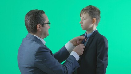 Man with suit arrange child tie and hair, father and son high five, green screen