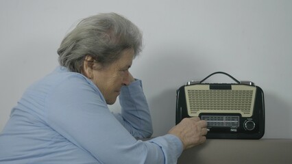 Old woman searching favorite station on retro radio