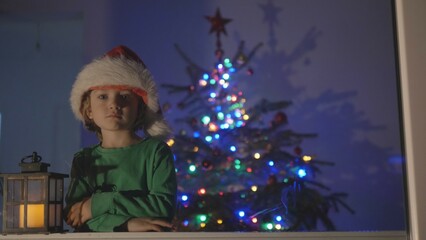 Funny little child with Santa Claus hat, boy play, lamp light in night