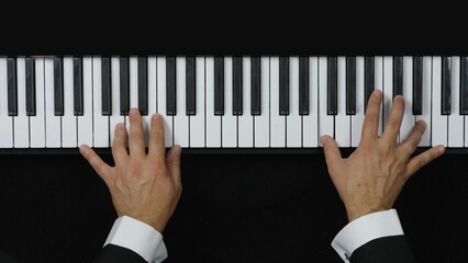 Detail of man hands with suit playing at piano, up view