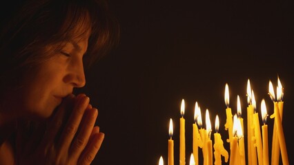 Portrait of detail woman face pray close lightning candles, black background