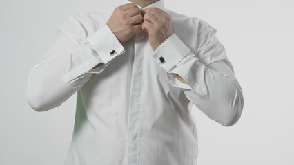 detail of man hands close the buttons from his white shirt