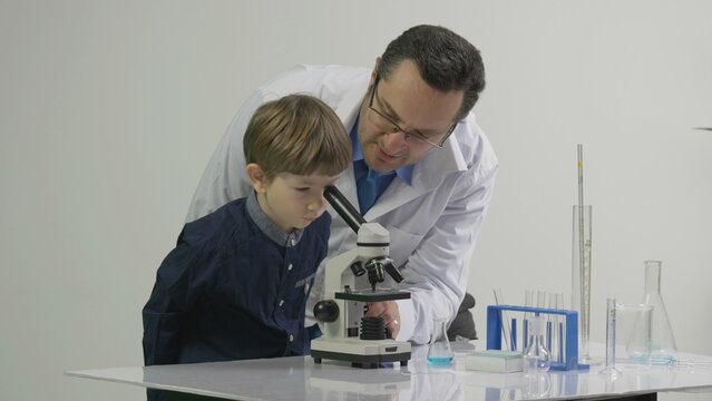 Laboratory technician teaching little child first lessons of chemistry