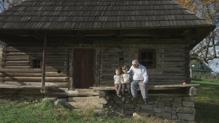Grandchildren enjoy time with their grandfather on the porch of the rural house