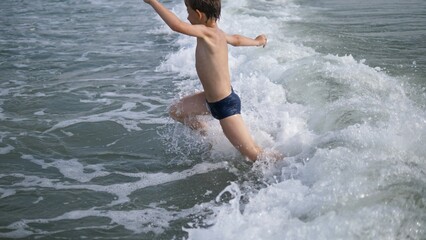 Child jump over sea waves, summer holiday fun