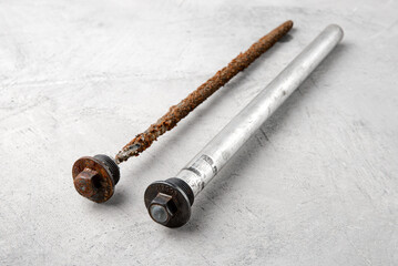 New and used rod to protect the boiler against rust on a gray concrete background.